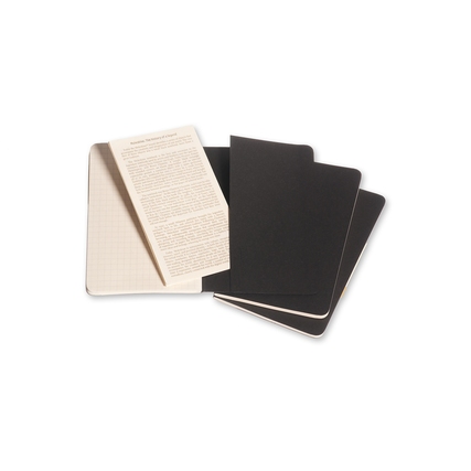 Drei schwarze Moleskine Notizhefte im Cahier-Stil, eines davon geöffnet, mit karierten Seiten.