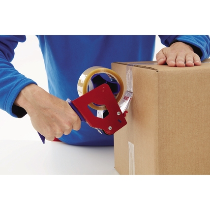 Hand hält ein rotes Abrollergerät mit transparentem Packband, das auf einen Karton angewendet wird.