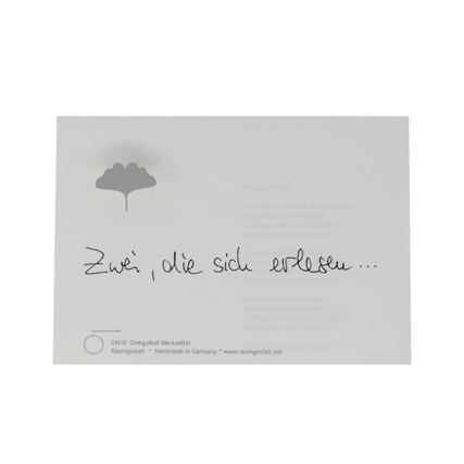 Notizblock mit handschriftlichem Text auf einem Eichenklotz und Ginkgo-Symbol.