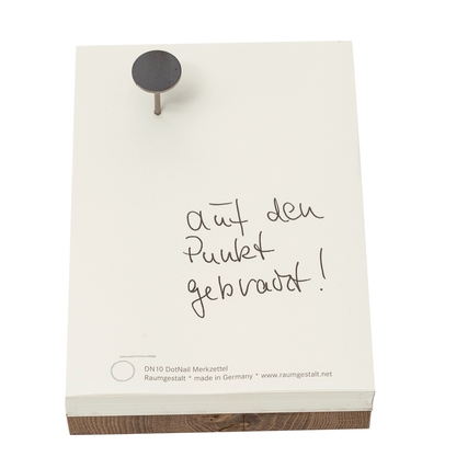 Notizblock aus Papier, fixiert mit einem Nagel auf einem Eichenklotz.
