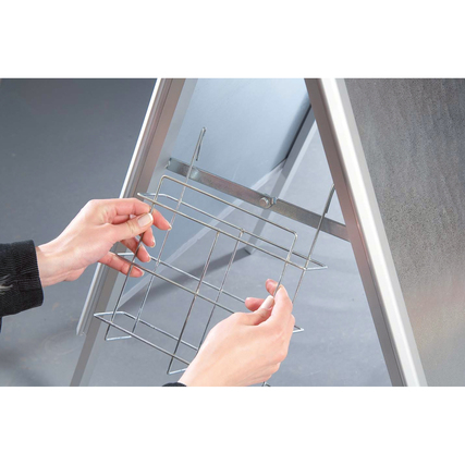 Eine Person befestigt einen Metallprospekthalter an einem Aufsteller.