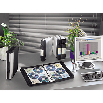 CD/DVD Hüllen in einem Ordner auf einem Schreibtisch mit Pflanzen und Monitor im Hintergrund.