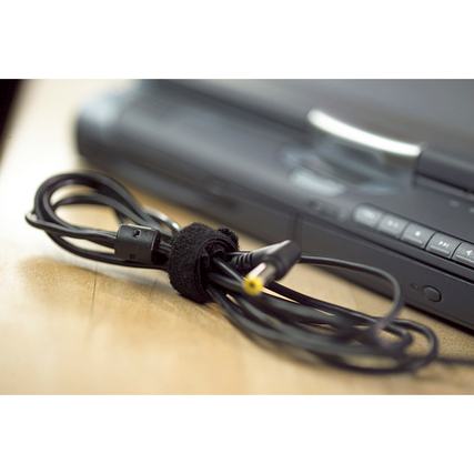 Kabelbinder hält zusammengebundene Kabel neben einem elektronischen Gerät auf einem Tisch.