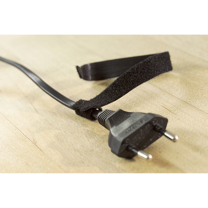 Schwarzer Kabelbinder um einen Stromstecker auf einem Holzuntergrund.