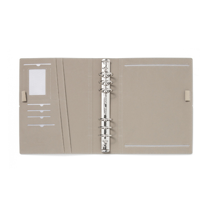 Offene Seitenansicht eines beige Filofax Organisers mit Ringen und Fächern.