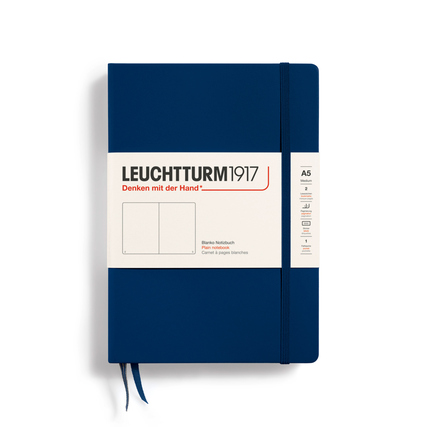Dunkelblaues Notizbuch im DIN A5-Format mit Aufkleber und elastischem Verschlussband.