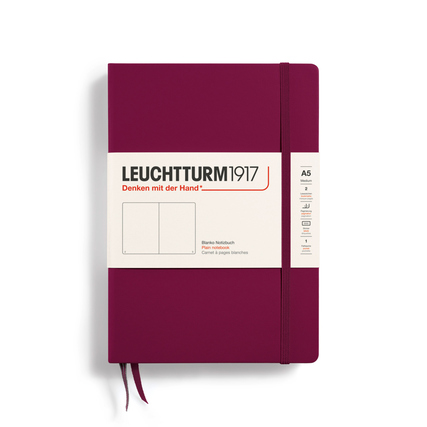 Rotes Notizbuch im A5-Format mit Band und einer Beschriftung auf dem Cover.