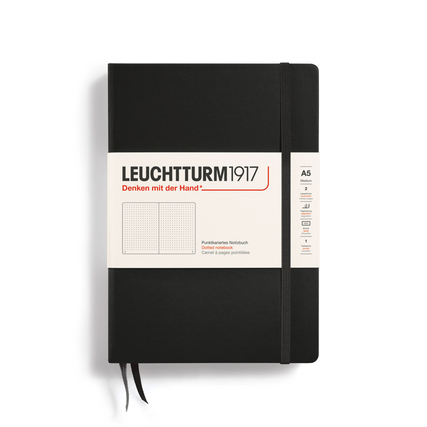 Schwarzes Notizbuch im DIN A5 Format mit einem hellen Etikett und einem Gummiband.
