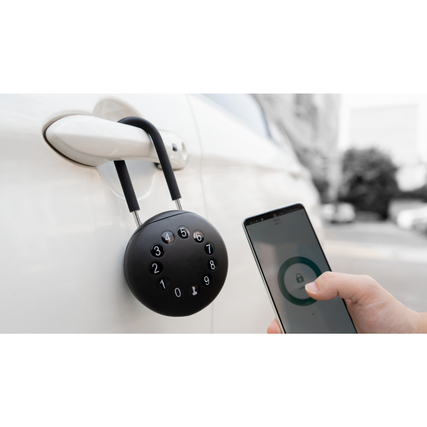 Schlüsselbox mit Vorhängeschloss-Bügel an einem Auto, Benutzer interagiert mit Smartphone.