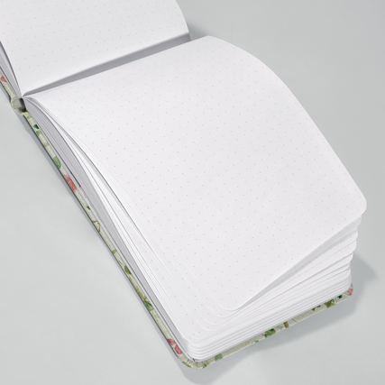 Offenes Notizbuch mit Punktlinien auf weißen Seiten und farbiger, floraler Umschlagkante.