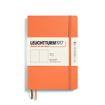Notizbuch in apricotfarbenem Softcover mit elastischem Verschluss und eingelegtem Etikett.