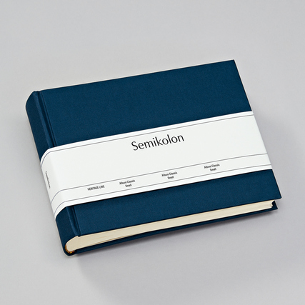 Fotoalbum in marineblauem Buchleinen mit einem bandförmigen Etikett um das Cover.