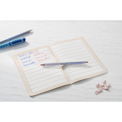 Buntstift Jumbo Grip bicolor liegt auf einem geöffneten Heft mit handschriftlichen Notizen.