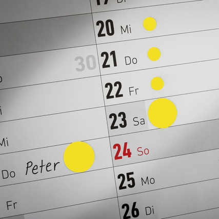 Gelbe Markierungspunkte auf einem Kalender zur Kennzeichnung von Terminen oder Hinweisen.