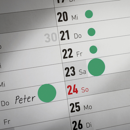 Grüne Markierungspunkte auf einem Kalender zur Kennzeichnung von Daten.