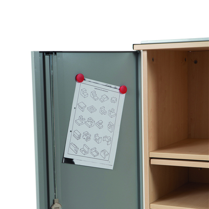 Ein Dokument mit Anleitungen hängt an der metallischen Tür eines Möbelstücks aus Buche.