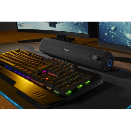 Bluetooth-Lautsprecher in schwarz neben einer RGB-Tastatur auf einem Schreibtisch.