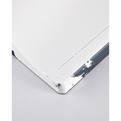 Detailansicht eines punktkarierten Notizbuchs mit abgerundeten Ecken und grafischem Cover.