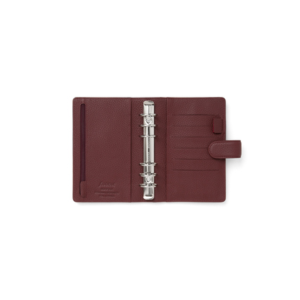 Dunkelroter, genarbter Organiser mit Ringen und mehreren Fächern im geöffneten Zustand.