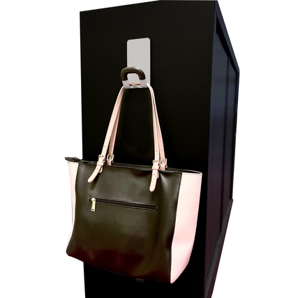 Der Garderobenhaken hält eine schwarze Handtasche an einer senkrechten schwarzen Fläche.