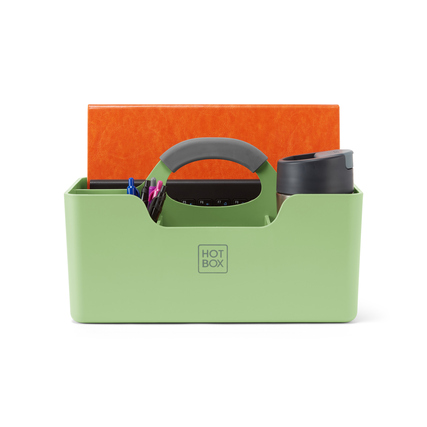 Grüne Organisationsbox mit Tragegriff, Fächern für Stifte und einer Tasse, dekorativ benutzt.