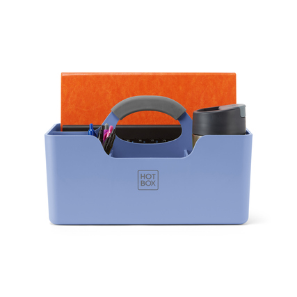 Blaue Organisationsbox mit Griff, gefüllt mit Stiften und einem Becher, auf einem Schreibtisch.