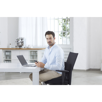 Mann sitzt an einem Tisch mit einem Laptop und benutzt ein Keilkissen auf einem Bürostuhl.