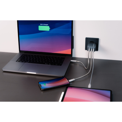Ladegerät mit Laptop, Smartphone und Tablet am Stromnetz in einer modernen Büroumgebung.