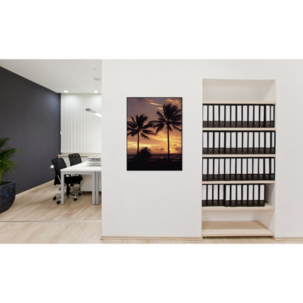 Dekobild mit Palmen und Sonnenuntergang an einer Büro Wand über einem Regal mit Aktenordnern.