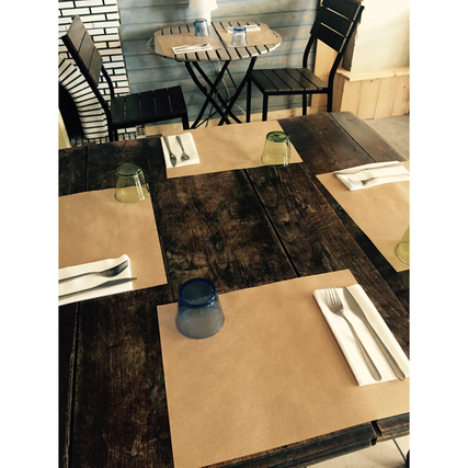 Tischgedeck mit mehreren PROnappe Tischsets aus satiniertem Papier auf einem Holztisch.