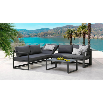 Moderne Loungemöbel in anthrazit mit Kissen und Glastisch vor einer Wasserlandschaft.