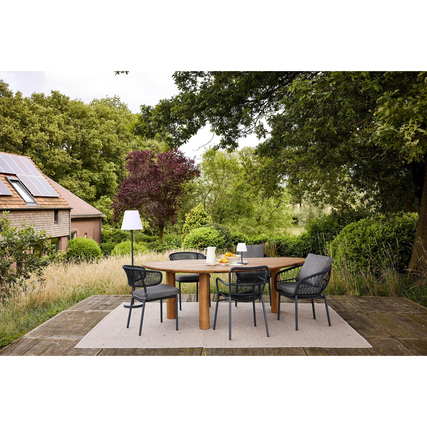 Gartenstuhl Ives in anthrazit auf einer Terrasse mit Esstisch und Umgebung aus Grünpflanzen.