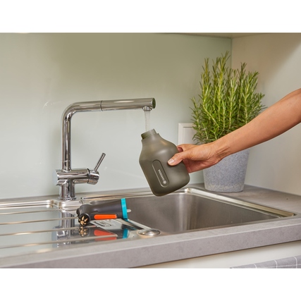 Pumpsprüher wird am Wasserhahn in eine Sprühflasche gefüllt, auf einer Küchenspüle abgestellt.