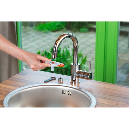 Eine Hand installiert einen Schlauchadapter an einen modernen Wasserhahn in einer Küchenumgebung.