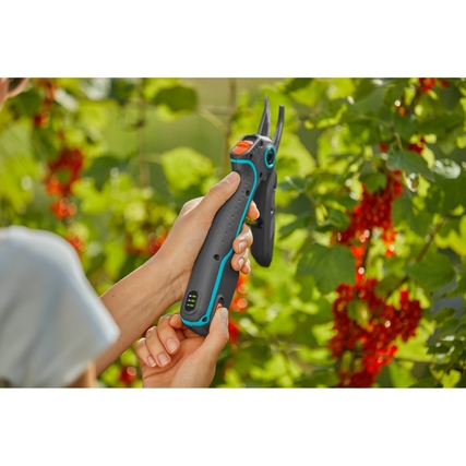 Frau schneidet mit der GARDENA AssistCut Gartenschere Sträucher in einem Garten.