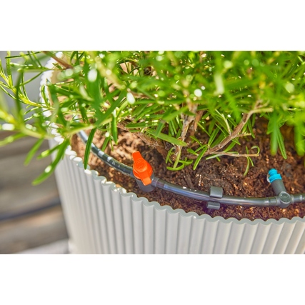 Tropfbewässerungssystem mit Rohren und Tropfern in einem Blumentopf.
