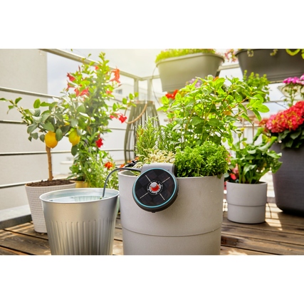 Bewässerungssystem AquaBloom an einem Blumentopf mit Wasserbehälter auf einem Balkon.