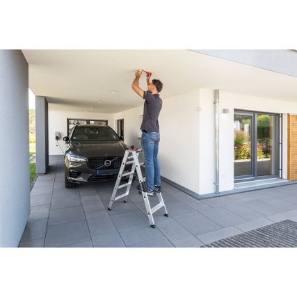 Person verwendet eine Stehleiter mit einer maximalen Arbeitshöhe von 2,7 m in einer Garage.
