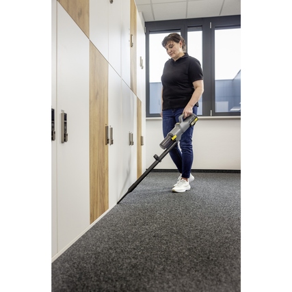 Bodenstaubsauger im Einsatz in einem Büro mit Teppichboden und Schränken im Hintergrund.