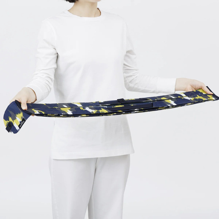 Eine Person hält eine gefaltete Shupatto Tragetasche in einer modernen, bunten Musterung.