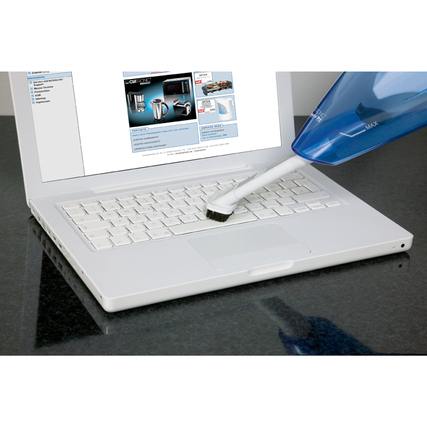Handstaubsauger reinigt die Tastatur eines Laptops auf einem schwarzen Tisch.
