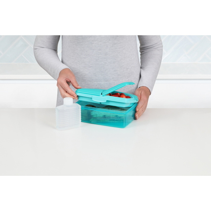 Frau hält eine farbige sistema Lunchbox mit mehreren Fächern und einer Flasche in der Hand.