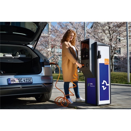 Frau lädt Elektroauto mit orangefarbenem LAPP Ladekabel an einem öffentlichen Ladegerät.