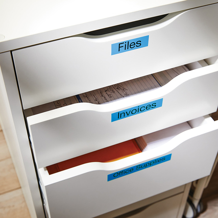 Blau-schwarze DYMO® D1 Etiketten auf einem weißen Schubladenschrank zur Beschriftung von Fächern.