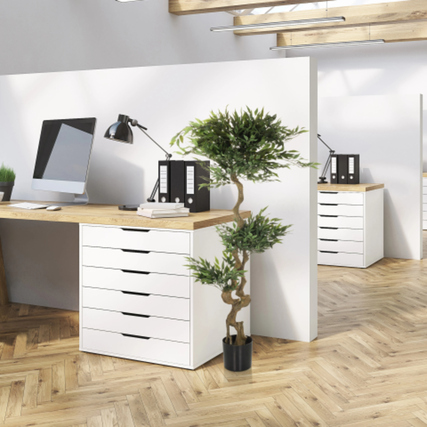 Künstliche Zimmerpflanze Acacia in einem schwarzen Kunststoff-Topf steht neben einem Schreibtisch.