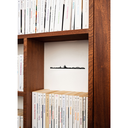 Schwarze Wanddekoration der Kölner Skyline in einem Bücherregal integriert.