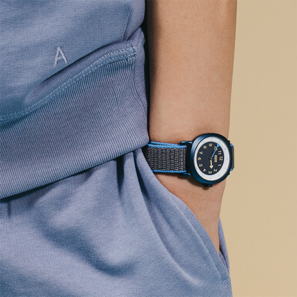 Armbanduhr TIKK Moon an einem Kinderhandgelenk, getragen mit einem blauen Klettband.