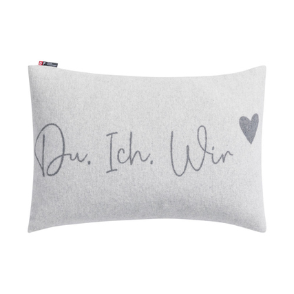 Grauer Kissenbezug mit dem Schriftzug "Du. Ich. Wir" und einem Herzen in der Ecke.
