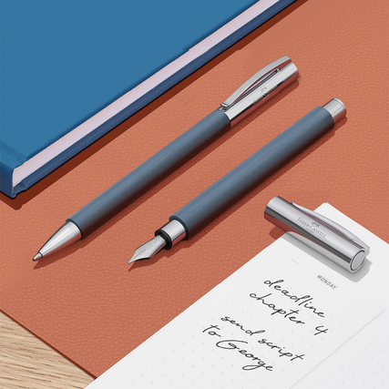 Kugelschreiber und Füllfederhalter auf einem Schreibtisch mit Notizbuch und Notizen.