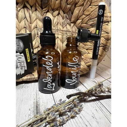 Zwei braune Glasflaschen mit Beschriftung und einem Acrylmarker auf einem Holzuntergrund.